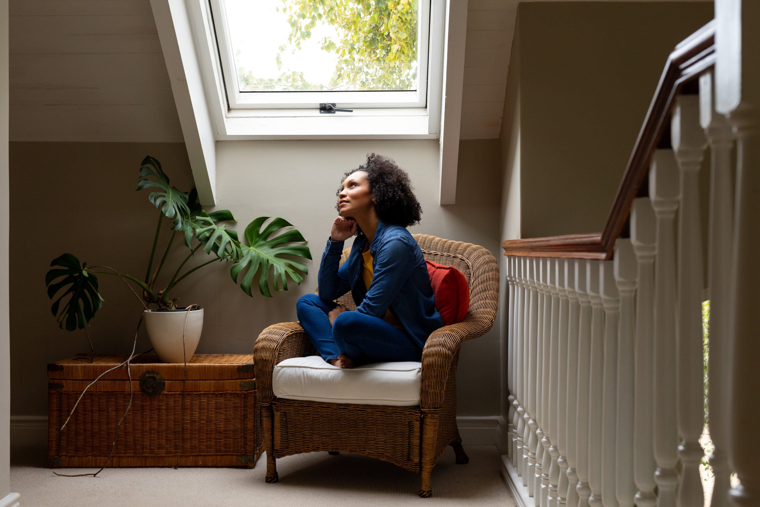 Woman sitting thoughtfully by window.